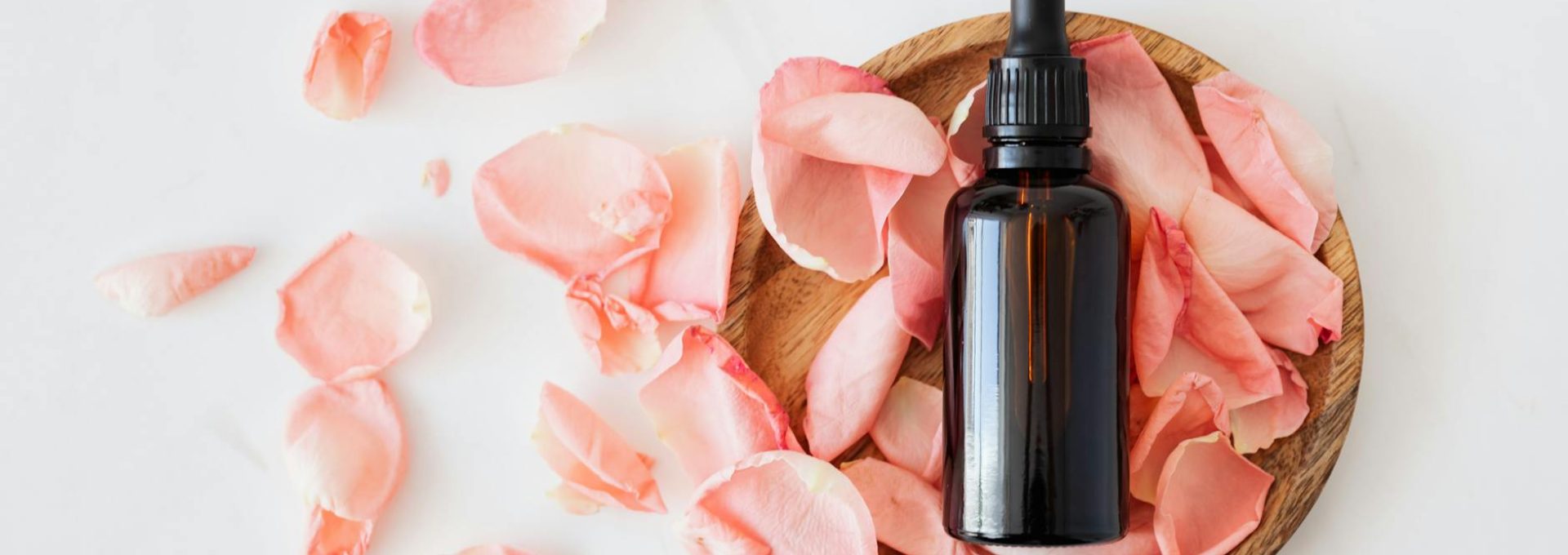composition of cosmetic bottle with pink rose petals and wooden plate
